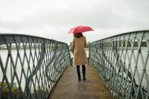 Visão traseira da mulher de pé com guarda-chuva na estação ferroviária — Fotografia de Stock