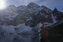 Escursionista donna in piedi con zaino sul lungolago durante l'inverno — Foto stock