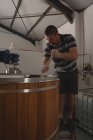 Чоловік працівник перемішуючи джин у винокурні на заводі — стокове фото