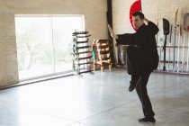 Man practicing with kung fu fan in fitness studio. — Stock Photo
