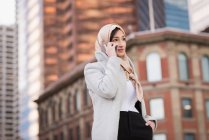 Femme en hijab parlant sur un téléphone portable en ville — Photo de stock
