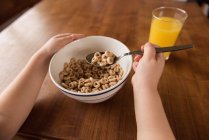 Menina tomando café da manhã cereal e suco na mesa em casa — Fotografia de Stock