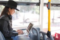Vista lateral da menina adolescente usando laptop no ônibus — Fotografia de Stock