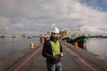 Trabajador portuario utilizando tableta digital en el astillero - foto de stock