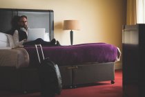Uomo d'affari che utilizza laptop sul letto in hotel — Foto stock