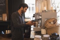 Barista usando portafilter enquanto prepara café na máquina de café no café — Fotografia de Stock