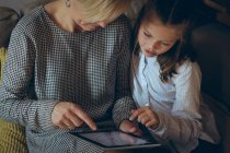 Мать и дочь с помощью цифрового планшета дома — стоковое фото