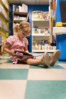 Cute girl reading book in store — Stock Photo