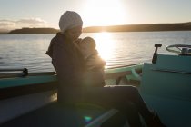 Mutter mit Baby auf Motorboot bei Sonnenuntergang unterwegs. — Stockfoto