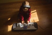 Маленький мальчик играет на пианино в спальне дома — стоковое фото