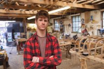 Мужчина плотник, стоящий со скрещенными руками в мастерской — стоковое фото