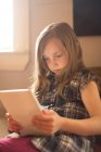 Mädchen sitzt auf Sofa und nutzt digitales Tablet zu Hause — Stockfoto