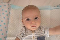 Close-up portrait of cute little baby lying on bed looking into camera at home — Stock Photo