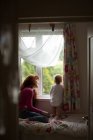 Mãe com sua menina olhando através da janela em casa — Fotografia de Stock
