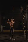 Vue arrière de la femme montrant son muscle dans la salle de gym — Photo de stock