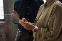 Compañeros de negocios discutiendo sobre tableta digital de vidrio . - foto de stock