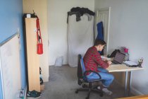 Junger Mann arbeitet mit Laptop am Schreibtisch im Wohnbereich. — Stockfoto