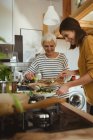 Lächelnde Seniorin und Tochter kochen zu Hause gemeinsam in der Küche — Stockfoto