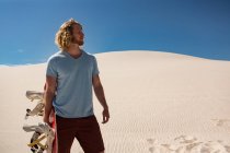 Чоловік з пісочницею, що стоїть в пустелі в сонячний день — стокове фото