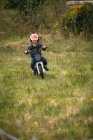 Маленький гонщик їде на велосипеді в саду — стокове фото