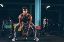 Homem musculoso exercitando com kettlebell no estúdio de fitness — Fotografia de Stock