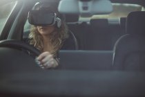 Belo executivo feminino usando fone de ouvido realidade virtual enquanto dirige um carro — Fotografia de Stock
