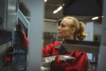 Trabajadora comprobando una máquina en fábrica - foto de stock
