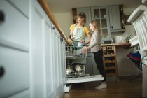 Mutter und Tochter ordnen zu Hause Utensilien in Küchenschränken — Stockfoto