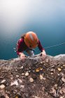 Скелястий альпініст досягає вершини скелі в сонячний день — стокове фото