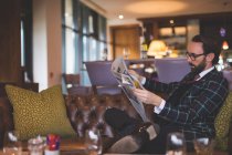 Businessman reading newspaper in hotel — Stock Photo