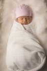 Neugeborenes in Mütze auf flauschiger Decke schlafend. — Stockfoto
