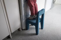 Niño de pie en la silla en la cocina en casa, sección baja . - foto de stock
