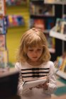 Unschuldiges Mädchen liest ein Buch im Laden — Stockfoto
