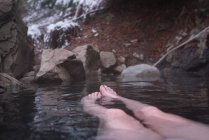 Low section of woman relaxing in hot spring during winter — Stock Photo