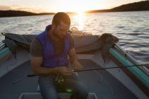 Attentif homme attachant canne à pêche en bateau à moteur . — Photo de stock