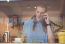 Чоловік розмовляє по мобільному телефону, снідаючи в кафе — стокове фото