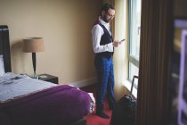 Homme d'affaires utilisant le téléphone portable dans la chambre d'hôtel — Photo de stock