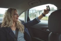 Junge Geschäftsfrau macht Selfie auf dem Rücksitz des Autos — Stockfoto