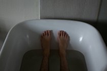 Section basse de l'homme se détendre dans la baignoire à la salle de bain — Photo de stock