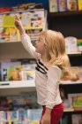 Fille pointant vers distant dans la librairie — Photo de stock