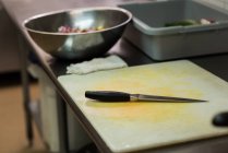 Primer plano de tabla de cortar y cuchillo en la cocina comercial - foto de stock
