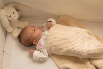 Новонародженої дитини відпочити під ковдрою в ліжко дитяче з плюшеві іграшки. — стокове фото