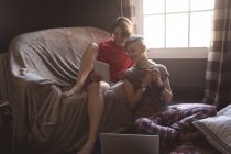 Mujeres jóvenes usando tableta digital en la sala de estar en casa . - foto de stock