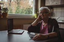 Gedachte Seniorin sitzt mit Blutdruckgerät und Laptop — Stockfoto