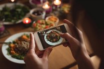 Mulher tirando foto de comida no celular em casa — Fotografia de Stock