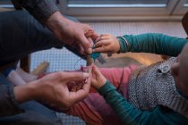 Padre insegna al figlio a lavorare a maglia con spillo e filo a casa . — Foto stock