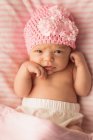 Новонародженої дитини в рожевий трикотажні капелюх розслабляючий на дитяче ліжко на дому. — стокове фото