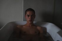 Portrait de jeune homme relaxant dans la baignoire à la salle de bain — Photo de stock