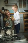 Mother and son arranging utensils in kitchen cabinets at home — Stock Photo