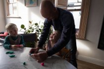 Батько і діти грають з глиною у вітальні вдома . — стокове фото